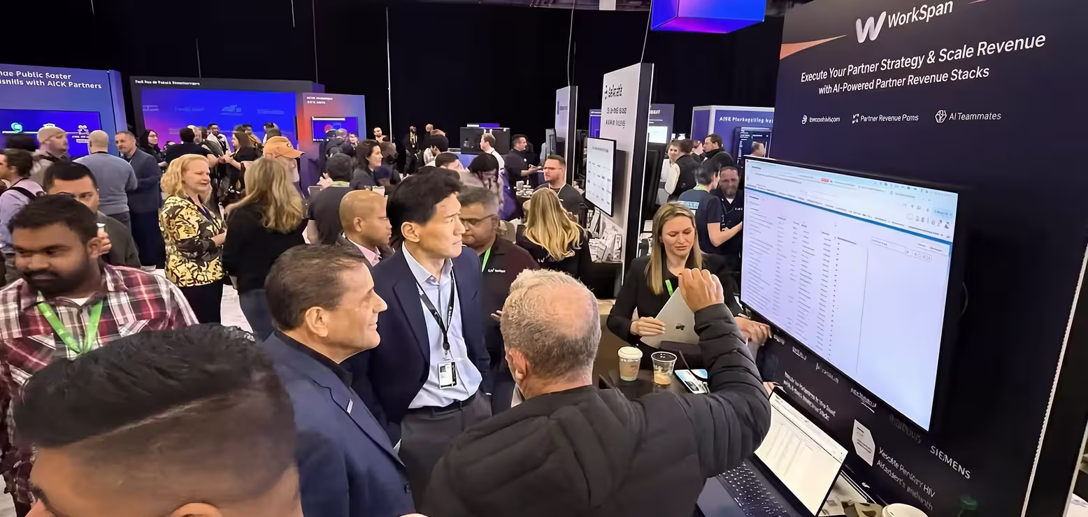 People gathered at a busy tech conference booth with large screen displaying data analytics.